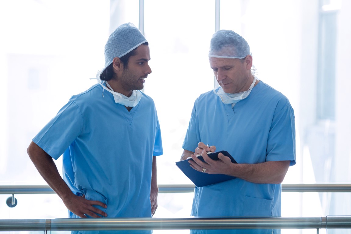 Surgeons discussing over medical reports in hospital corridor
