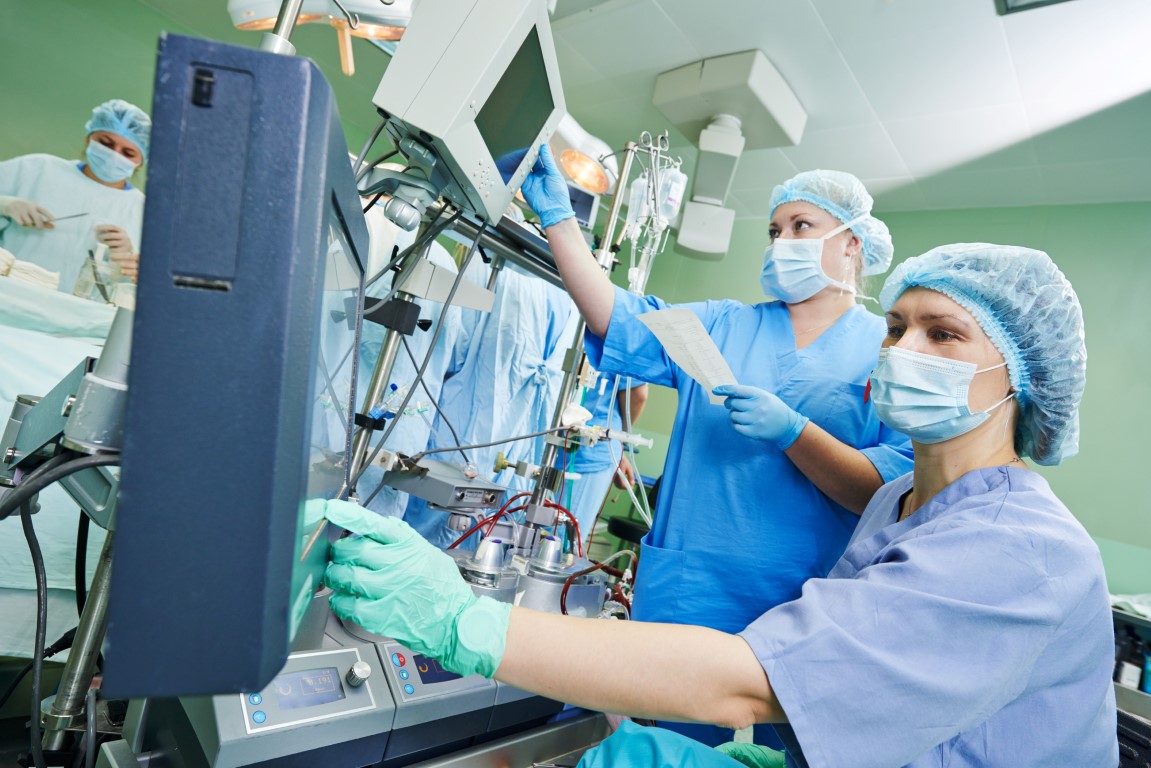 Surgery assistant nurse working with artificial cardiac valve at operation in cardiology clinic