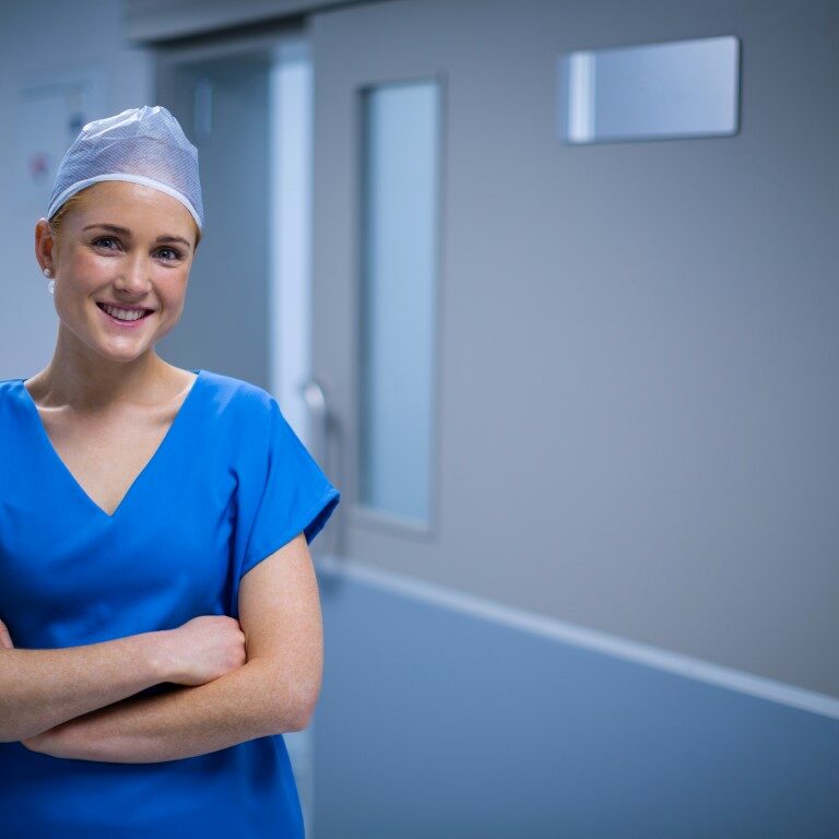 Portrait of female nurse standing with arms crossed in corridor of hospital